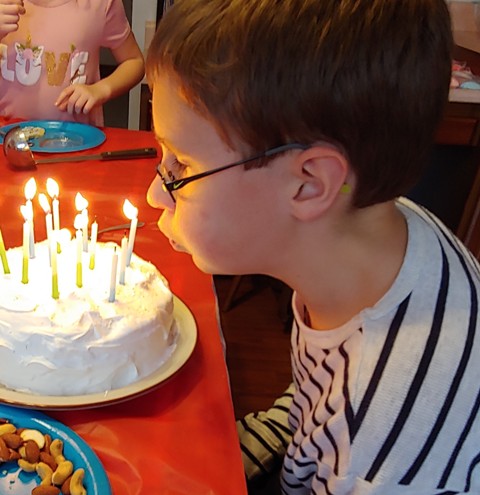The birthday boy blowing out the candles on the cake.