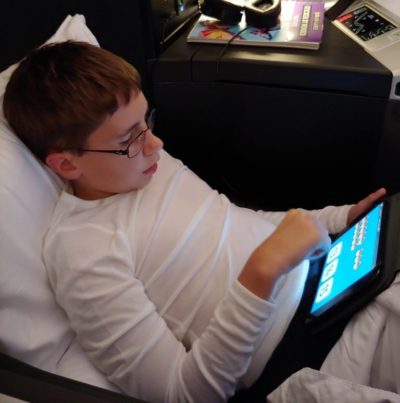 Boy playing on iPad during flight.