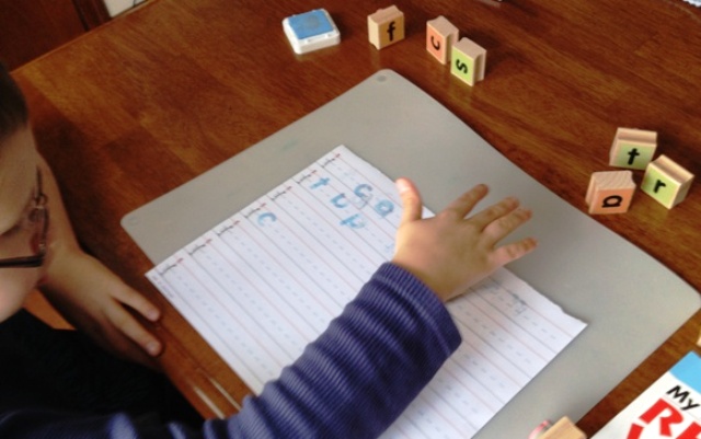 Child using stamps to spell words.