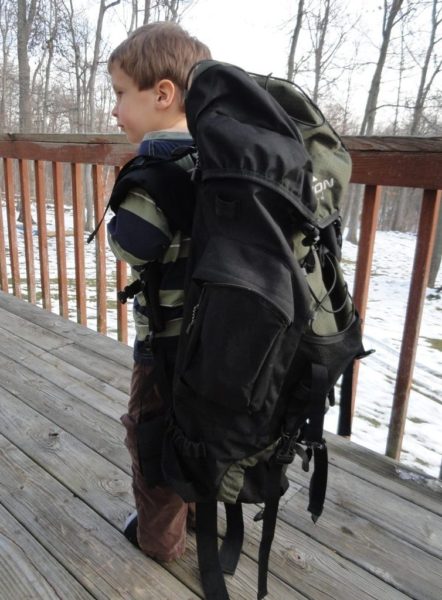 Little boy wearing large backpack.