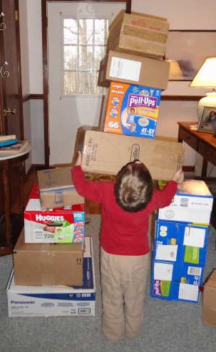Little boy making a tower of boxes. 