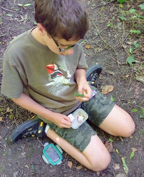 Boy find swag on a geocaching treasure hunt.