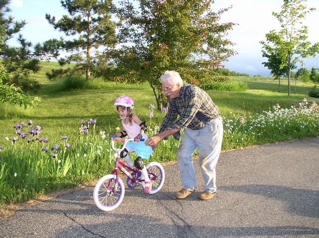 Grandparent teaching child to ride a bike.