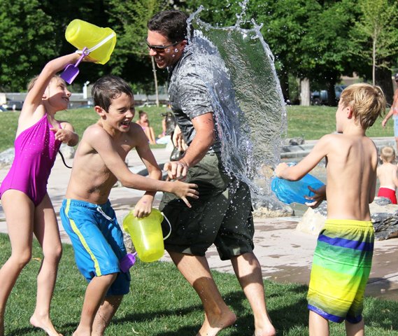 Kids socializing and having a water fight with buckets.