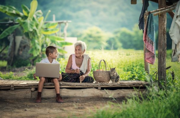 Grandmother sits with grandson on a laptop.