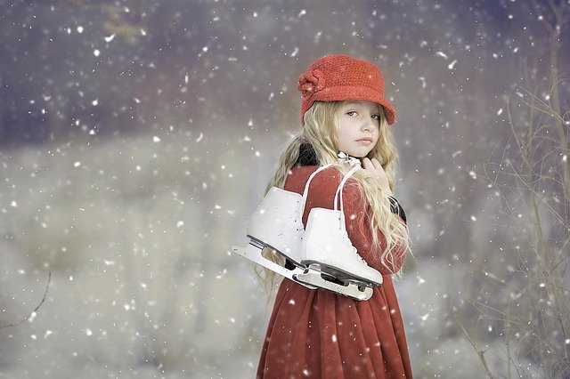 Little girl with ice skates. Snow precipitation.